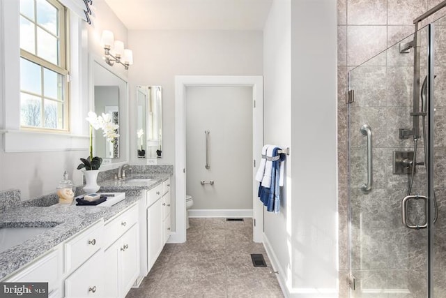 full bath featuring double vanity, a stall shower, a sink, and toilet