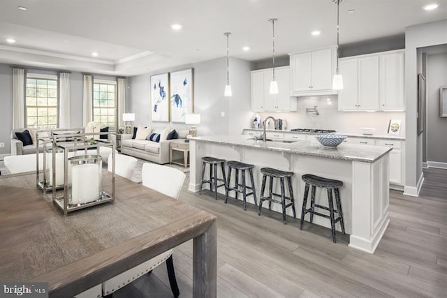 kitchen featuring open floor plan, a breakfast bar, wood finished floors, and a sink