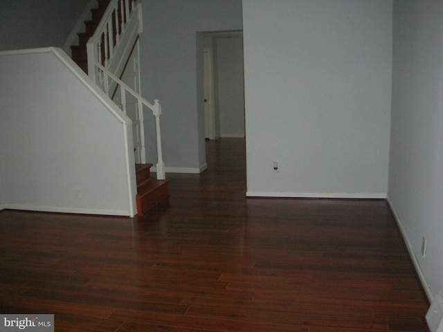 empty room featuring stairs, baseboards, and wood finished floors