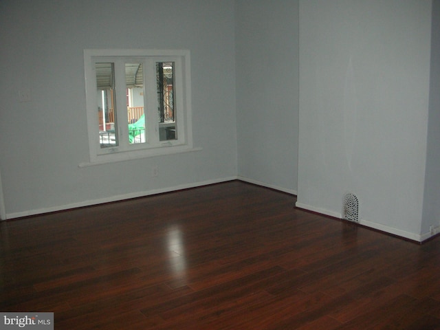 empty room featuring baseboards and dark wood-style flooring