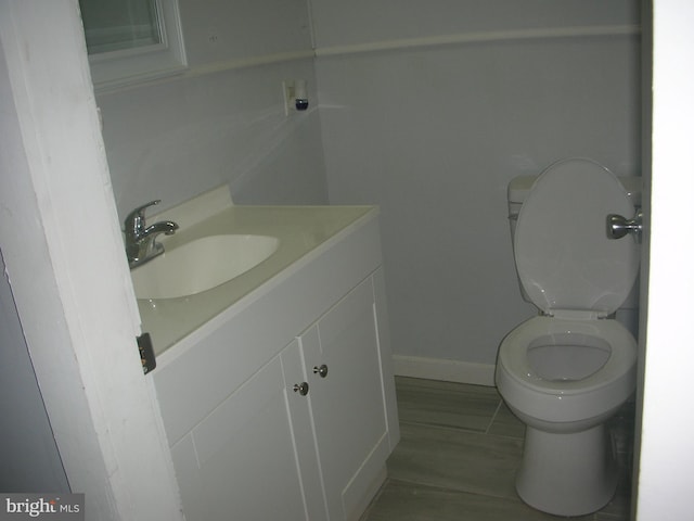 bathroom with baseboards, vanity, and toilet