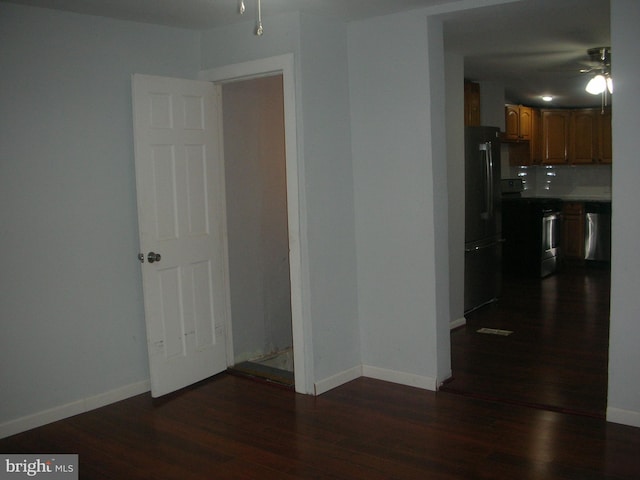 spare room with dark wood-type flooring and baseboards