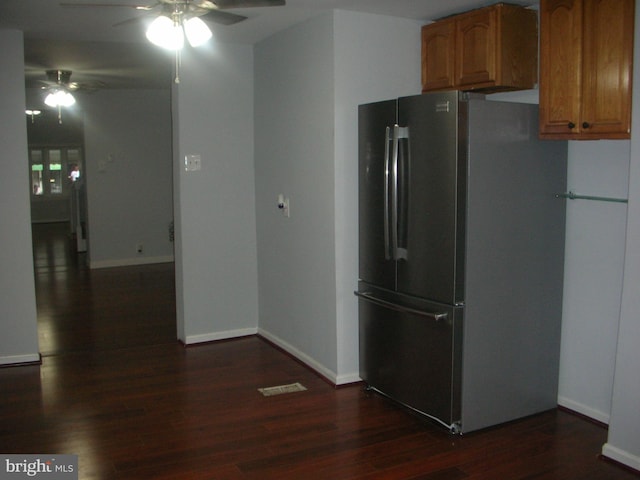 kitchen featuring baseboards, brown cabinetry, dark wood-style floors, ceiling fan, and freestanding refrigerator