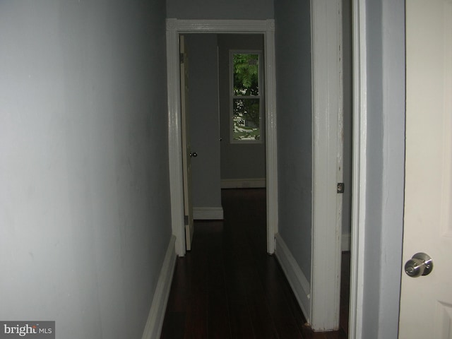 hall featuring dark wood-style flooring and baseboards