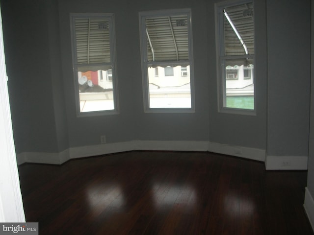 unfurnished room with dark wood-style floors and baseboards