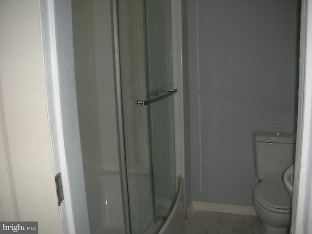 full bathroom featuring toilet, marble finish floor, baseboards, and a shower with door