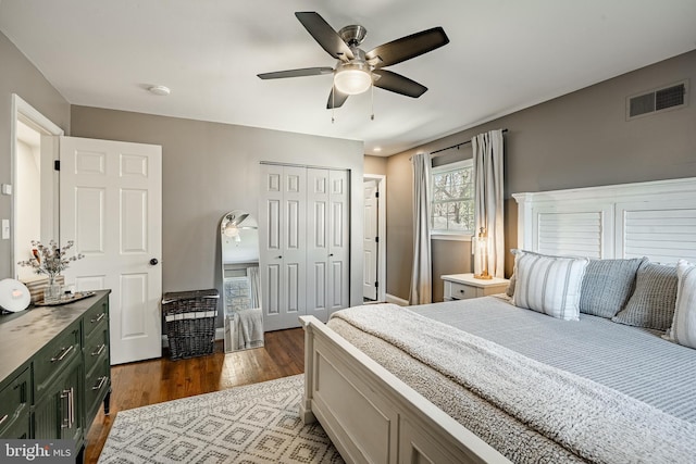 bedroom with a closet, visible vents, dark wood-type flooring, and a ceiling fan