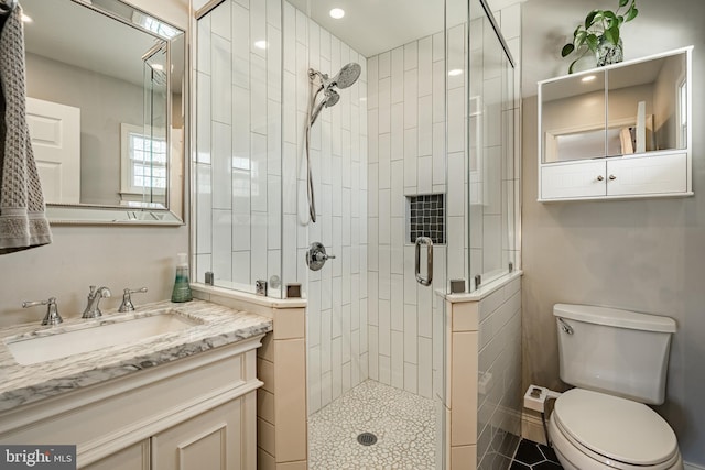 bathroom with toilet, a stall shower, and vanity