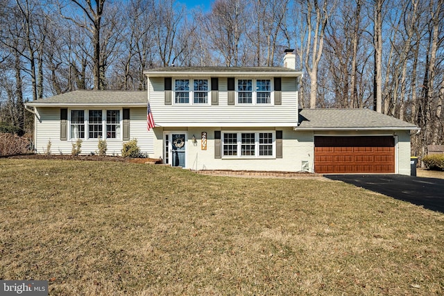 tri-level home featuring a front lawn, an attached garage, aphalt driveway, and a chimney