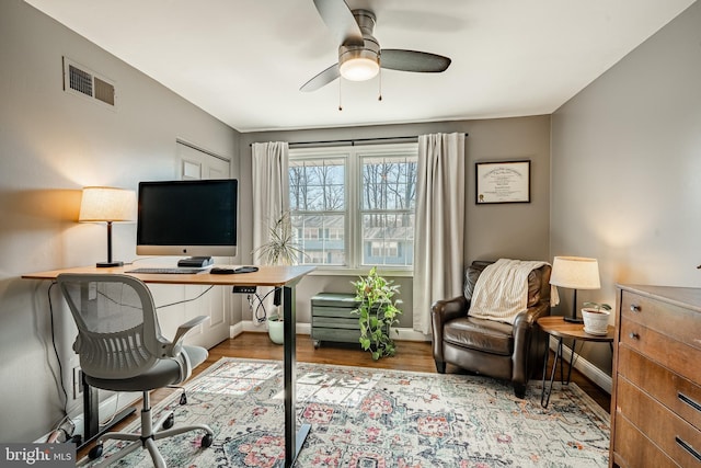 home office with visible vents, baseboards, ceiling fan, and wood finished floors