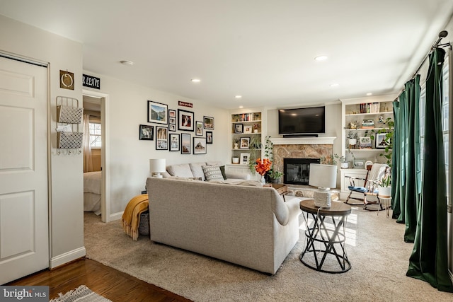 living area with recessed lighting, a fireplace, baseboards, and wood finished floors