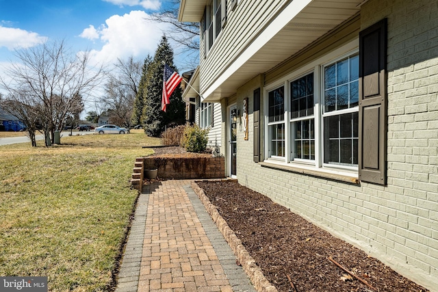 view of side of property with brick siding and a lawn