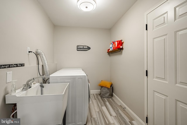 laundry room with light wood-style flooring, washer and clothes dryer, a sink, baseboards, and laundry area