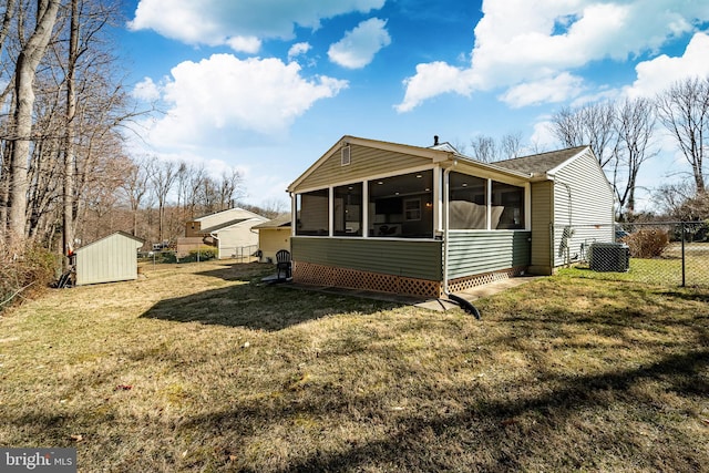 view of side of home featuring fence, a shed, a lawn, an outdoor structure, and a sunroom