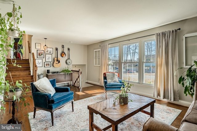 living area with baseboards, wood finished floors, and stairs