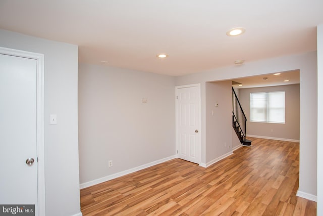 spare room with light wood-type flooring, baseboards, stairway, and recessed lighting