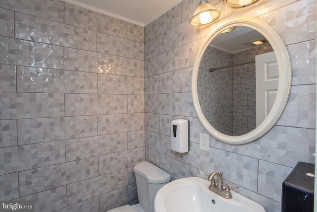 bathroom with toilet, a sink, and tile walls