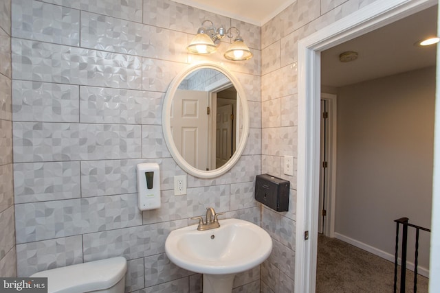 bathroom with baseboards, a sink, tile walls, and toilet