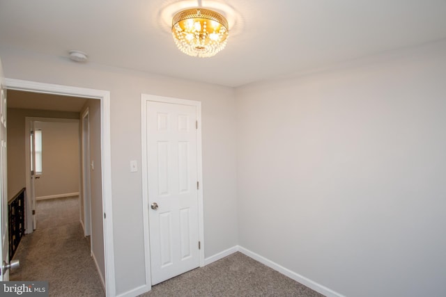 interior space featuring a chandelier, carpet flooring, and baseboards