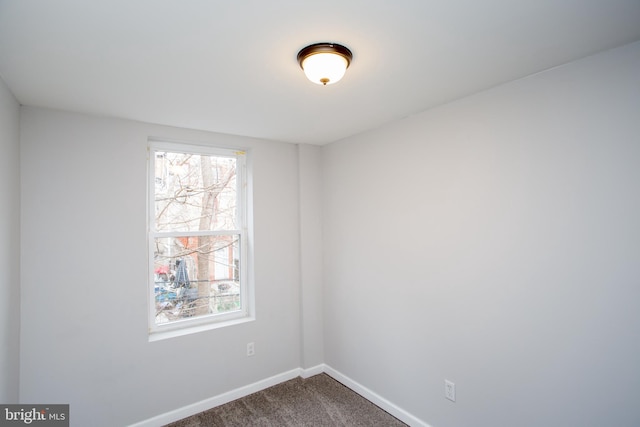 spare room with dark carpet and baseboards