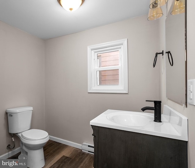 bathroom with toilet, a baseboard heating unit, vanity, wood finished floors, and baseboards