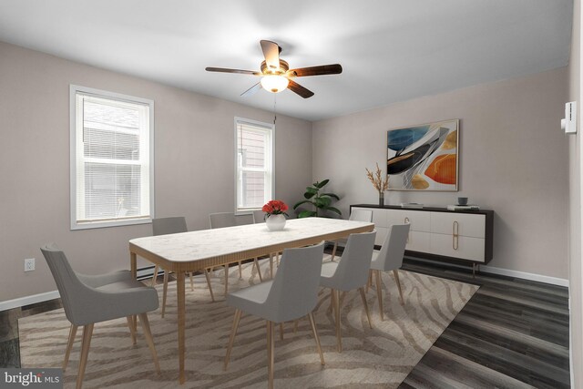 dining space with baseboard heating, wood finished floors, a ceiling fan, and baseboards