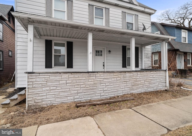 multi unit property featuring stone siding and covered porch