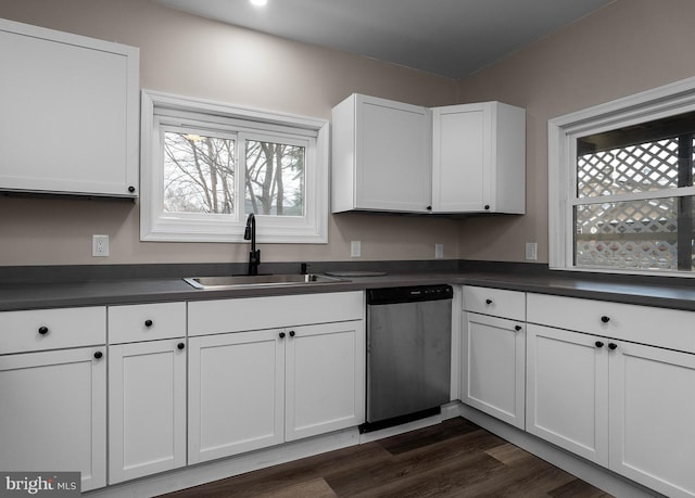 kitchen with dark countertops, white cabinetry, dishwasher, and a sink