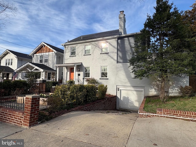 view of front of property with concrete driveway, a chimney, fence, brick siding, and a garage
