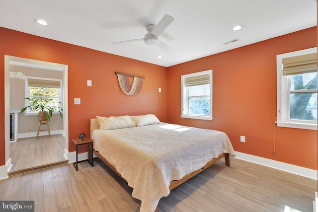 bedroom featuring light wood-style floors, baseboards, multiple windows, and visible vents