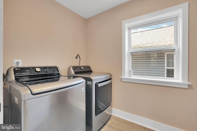clothes washing area featuring baseboards, washing machine and dryer, wood finished floors, and laundry area