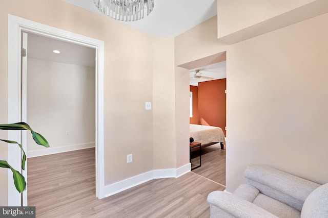interior space featuring baseboards, wood finished floors, and ceiling fan with notable chandelier