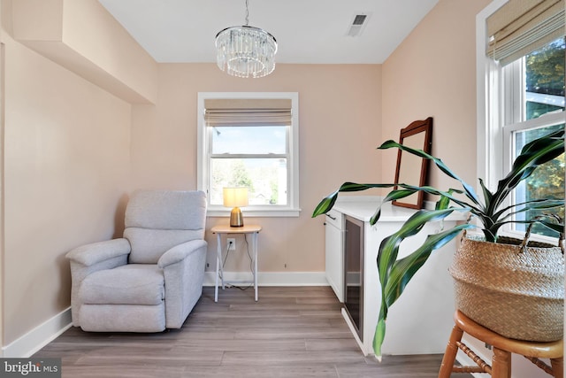 sitting room with baseboards, visible vents, light wood-style flooring, and a chandelier