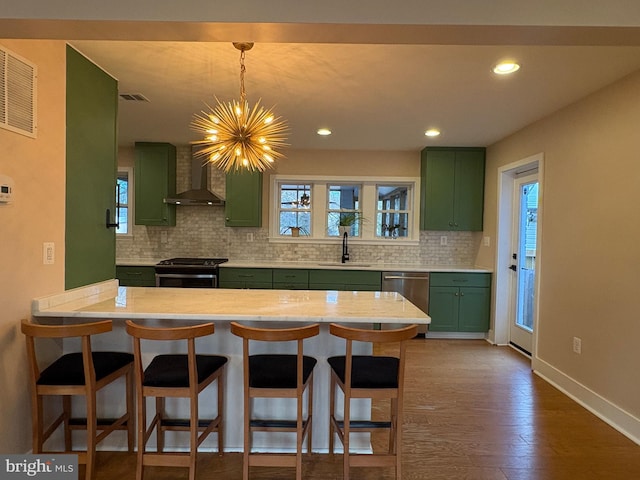 kitchen featuring light countertops, a sink, green cabinets, tasteful backsplash, and stainless steel appliances