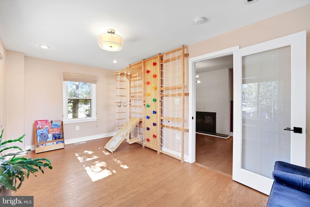 game room with baseboards, a large fireplace, wood finished floors, and recessed lighting