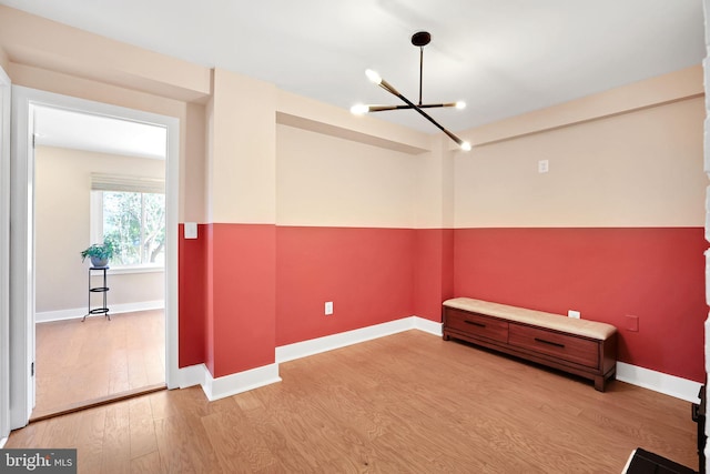 unfurnished room featuring baseboards, wood finished floors, and an inviting chandelier