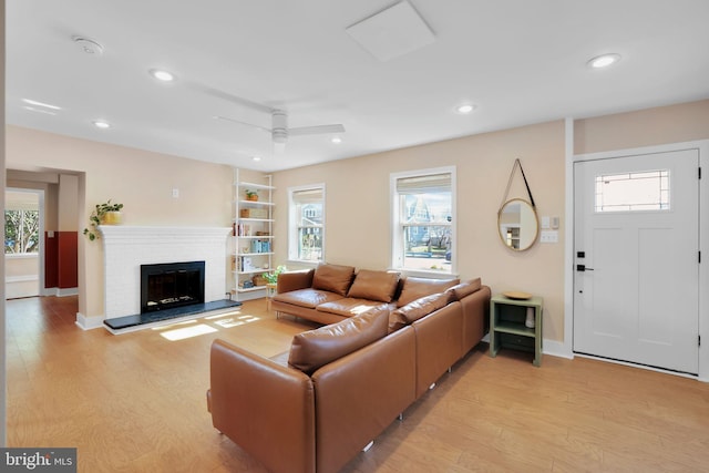 living area with a brick fireplace, plenty of natural light, light wood finished floors, and recessed lighting