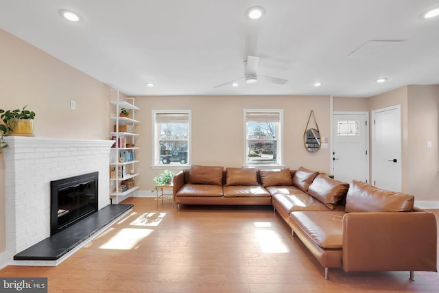 living room with wood finished floors, ceiling fan, recessed lighting, and a brick fireplace