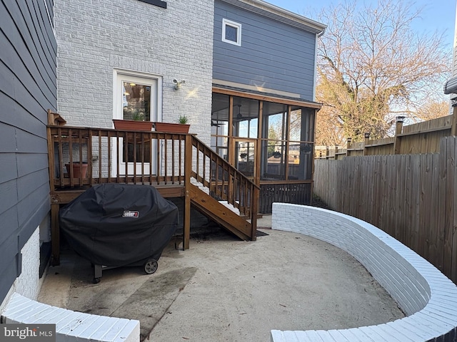 exterior space with fence, a wooden deck, a sunroom, and a patio