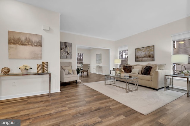 living area with crown molding, baseboards, and wood finished floors