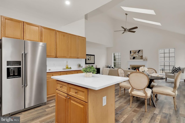 kitchen with a ceiling fan, a lit fireplace, light countertops, light wood-style floors, and high quality fridge