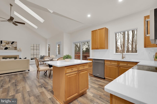 kitchen featuring light wood finished floors, a center island, dishwasher, a ceiling fan, and a sink