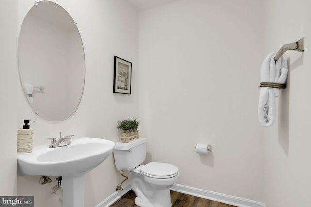 half bathroom featuring toilet, baseboards, and wood finished floors