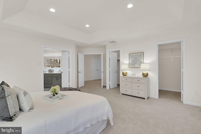 bedroom featuring visible vents, recessed lighting, a raised ceiling, light colored carpet, and a spacious closet