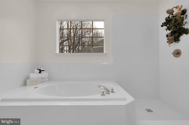 bathroom featuring tiled shower and a bath