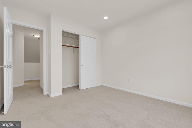 unfurnished bedroom with recessed lighting, light colored carpet, baseboards, and a closet