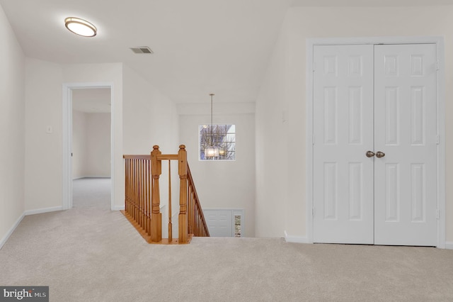 hallway with an inviting chandelier, carpet flooring, an upstairs landing, and visible vents