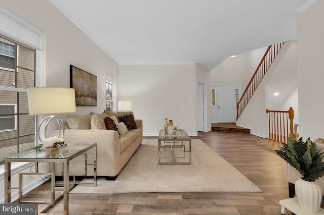 living room featuring stairway, wood finished floors, baseboards, and ornamental molding