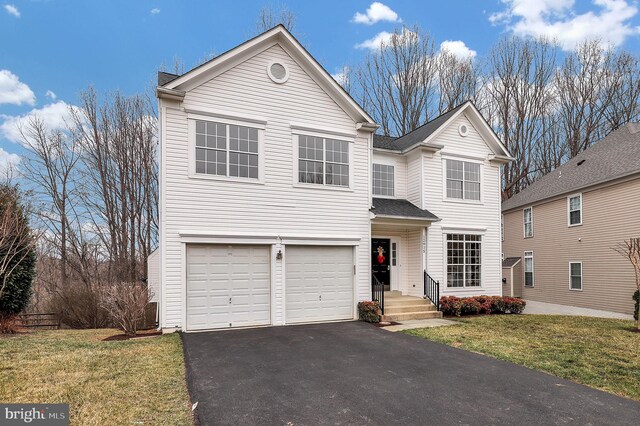 traditional-style house featuring driveway, an attached garage, a front lawn, and a shingled roof