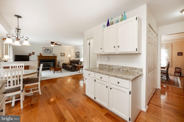 kitchen with a glass covered fireplace, light wood-style flooring, open floor plan, and white cabinets